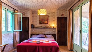 Une chambre à coucher avec un lit, un luminaire suspendu, une fenêtre avec des rideaux et une porte.