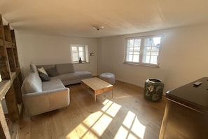 A living room with a sofa, a coffee table, a lamp, a window, and a trash can. - Old nail forge Bremm (Bremm)