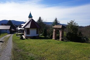 Eine ländliche Kirche mit einem Kirchturm, einem kleinen Steinbau und einem Kiesweg.