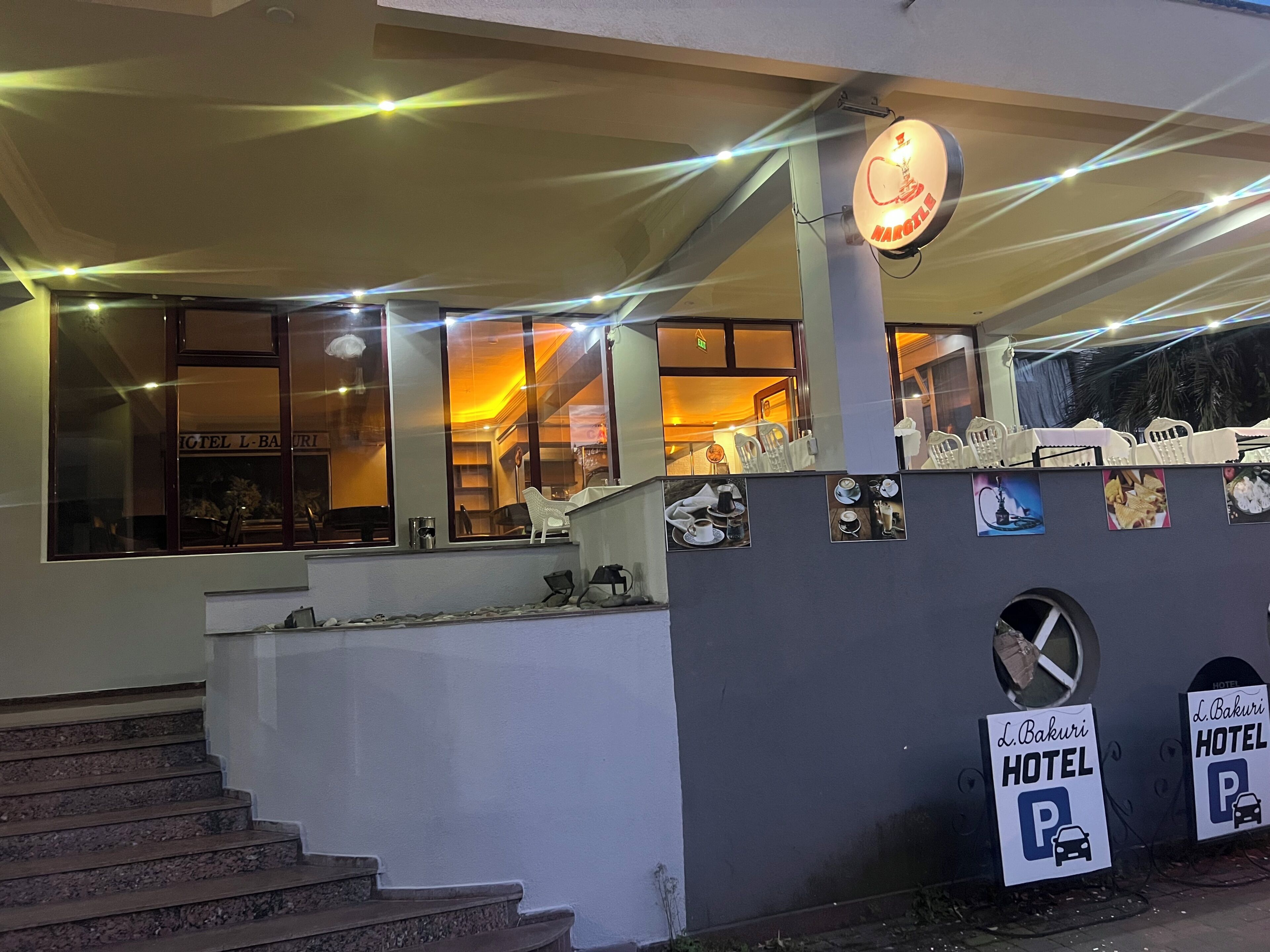 L’entrée d’un hôtel, avec un escalier, un panneau indiquant un espace de stationnement et un panneau mural portant un logo.