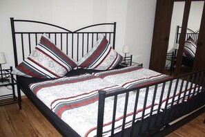 A bed with a metal frame, patterned bedding, and two bedside lamps. - Holiday apartment with 1 bedroom (Olsberg)