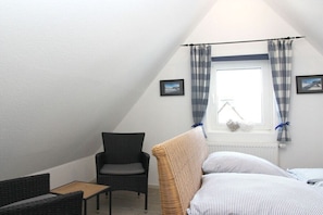 A small, triangular room with a bed, a chair, a table, and a window with curtains. - Holiday home Olsberg (Olsberg)