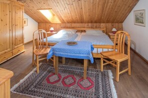 Een gezellig slaapkamer op zolder met houten wanden en een schuine hemel, met twee bedden, een klein tafeltje en een stoel.