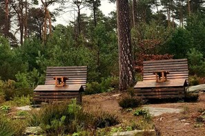 Zwei Holzhütten mit Bänken, umgeben von dichtem Wald.