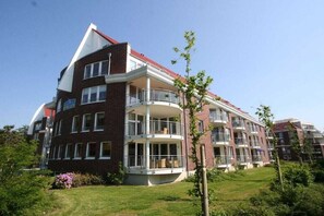 A multi-story residential building with balconies, a brick facade, and a green lawn. - Holiday apartment with 2 bedrooms (Cuxhaven)