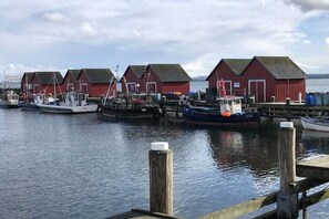 Ein Hafen mit mehreren roten Gebäuden, vor Anker liegenden Booten und ruhigem Wasser.