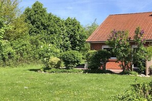 Ein Wohnhaus mit rotem Ziegeldach, umgeben von üppiger Vegetation und einem gepflegten Rasen.