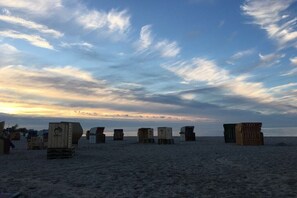 A beach with several wooden structures, possibly beach huts, and a clear sky.