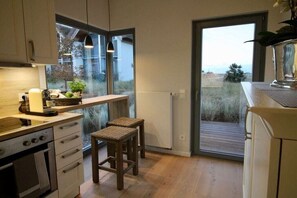 A compact kitchen with a built-in oven, a small island, and a view through a glass door.