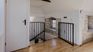 Un escalier avec des murs en pierre, un plancher en bois et une rampe en métal noir.