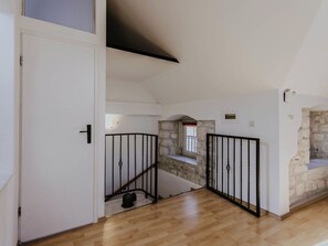 Eine Treppe mit Steinwänden, Holzboden und einem schwarzen Metallgeländer.