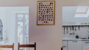 Une cuisine avec des meubles blancs, un puits de lumière et un tableau représentant différents animaux accroché au mur.