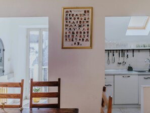 Eine Küche mit weißen Schränken, einem Oberlicht und einem Bilderrahmen mit verschiedenen Tiergesichtern an der Wand.