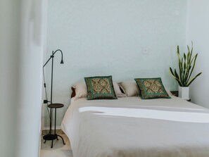 A bedroom with a bed, two decorative pillows, a floor lamp, a potted plant, and a wall socket. - Vacation home Nerium by Interhome (Trogir)