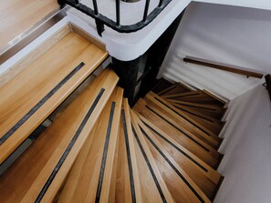 A wooden staircase with black stripes, a metal handrail, and a white wall. - Vacation home Nerium by Interhome (Trogir)