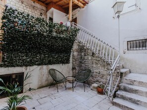 A stone staircase leading to a wooden deck, surrounded by a white wall and a green ivy-covered fence. - Vacation home Nerium by Interhome (Trogir)