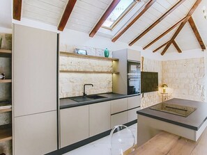 A modern kitchen with stone walls, a skylight, and a built-in oven. - Apartment Nerium by Interhome (Trogir)