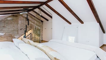 Ein Schlafzimmer mit Steinwand, einer Glastreppe und einem Bett mit weißer Bettwäsche.