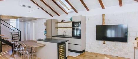 A modern kitchen with a built-in oven and a TV mounted on the wall.