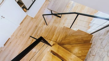 Ein modernes Interieur mit einer Holztreppe, weißen Wänden und einer Wand als Steinakzent.