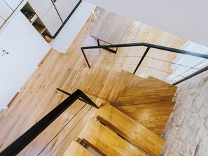 Un intérieur moderne avec un escalier en bois, des murs blancs et un mur d’accent en pierre.