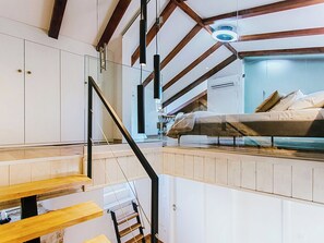 Une petite pièce comprenant un lit superposé, un escalier et un ventilateur de plafond.