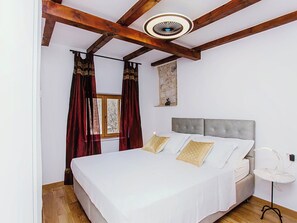 Quarto com cama, cortinas, parede de pedra e ventilador de teto.