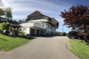 Una casa a due piani con un balcone, una strada privata e un'auto parcheggiata.