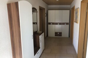 Un corridoio con un armadio, uno specchio e una porta.