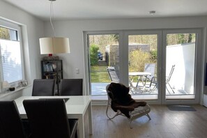 En modern inredning med ett matområde, en soffa och en skjutdörr i glas som leder ut till en uteplats.