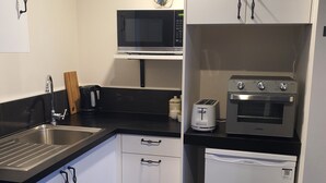 A compact kitchen with a sink, microwave, toaster, and small refrigerator. - Omokoroa Sea View Apartment, stunning views, amazing sun rises, quiet spot (Ōmokoroa)