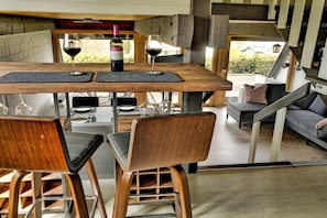 A modern dining area with a wooden table, two chairs, and a wine bottle.