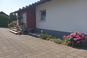 A house with a red and white exterior, a front porch with steps, and a small window. - Maria Rosa Holiday Apartment (Sandberg)