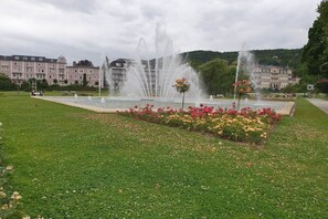 A fountain surrounded by flower beds in a park with buildings in the background. - Maria Rosa Holiday Apartment (Sandberg)