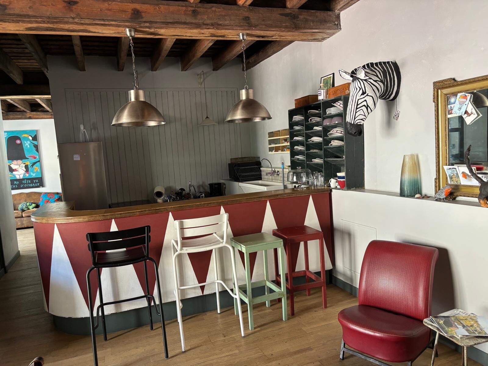 A kitchen with a bar area, wooden ceiling beams, and a zebra-patterned wall decoration.