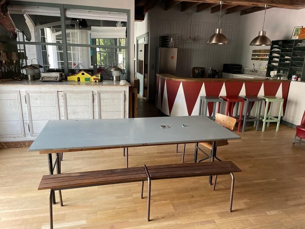 Una cocina con una isla grande, mesa de madera y bancos.
