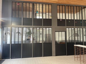 A modern building with large windows, a tiled floor, and a visible kitchen area. - L'Houmeau post house (Angoulême)