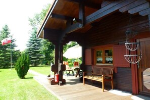 Eine Holzdiele mit Veranda, Sitzgelegenheit im Freien und einer Flagge.