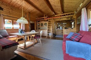 Ein Holzblockhaus Innenansicht mit Essbereich, einem roten Sofa und einer Küchenzeile.