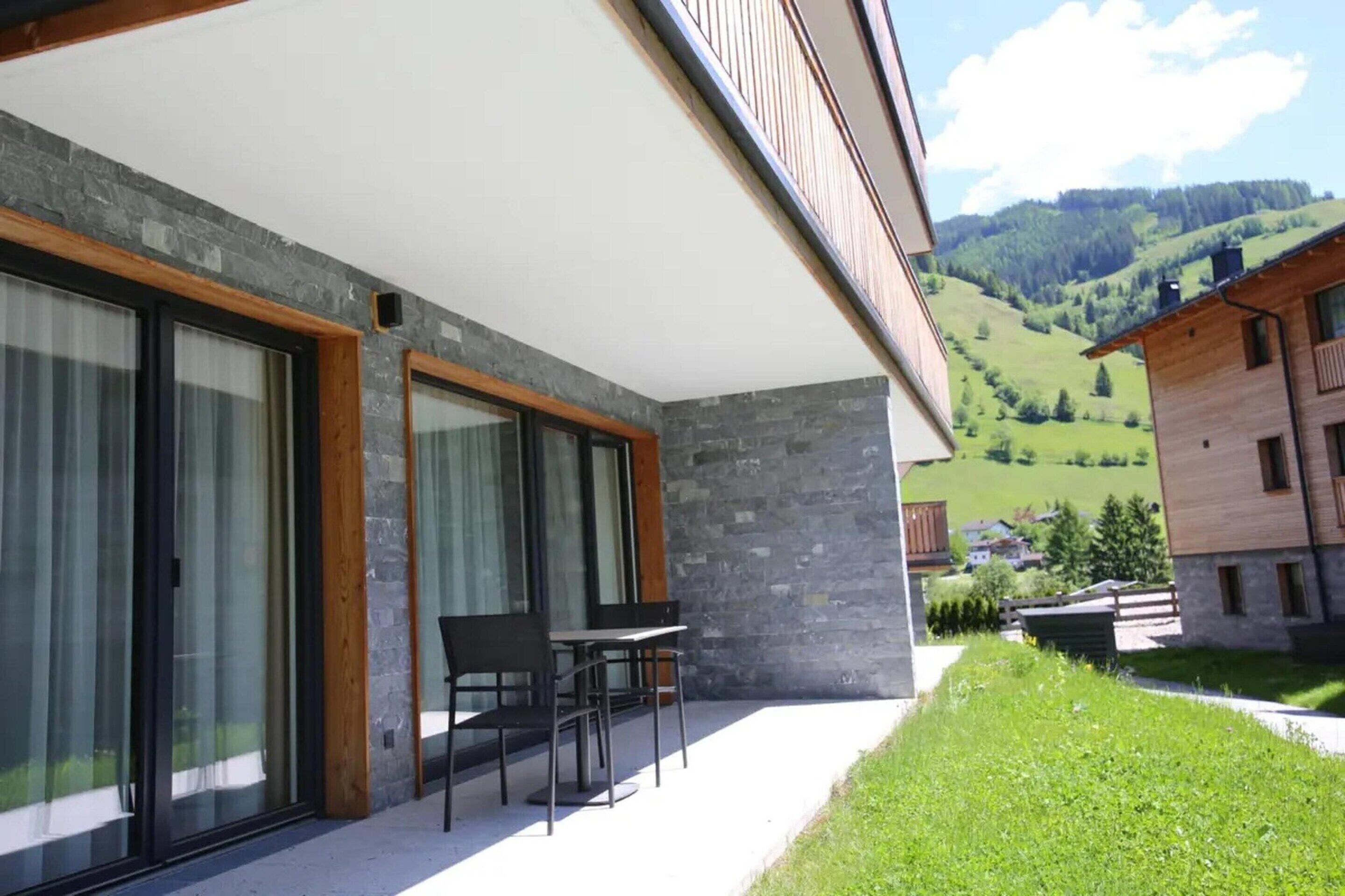 Un edificio moderno con amplios ventanales, fachada de piedra y vistas a un valle verde.