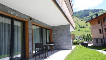 Un edificio moderno con amplios ventanales, fachada de piedra y vistas a un valle verde.