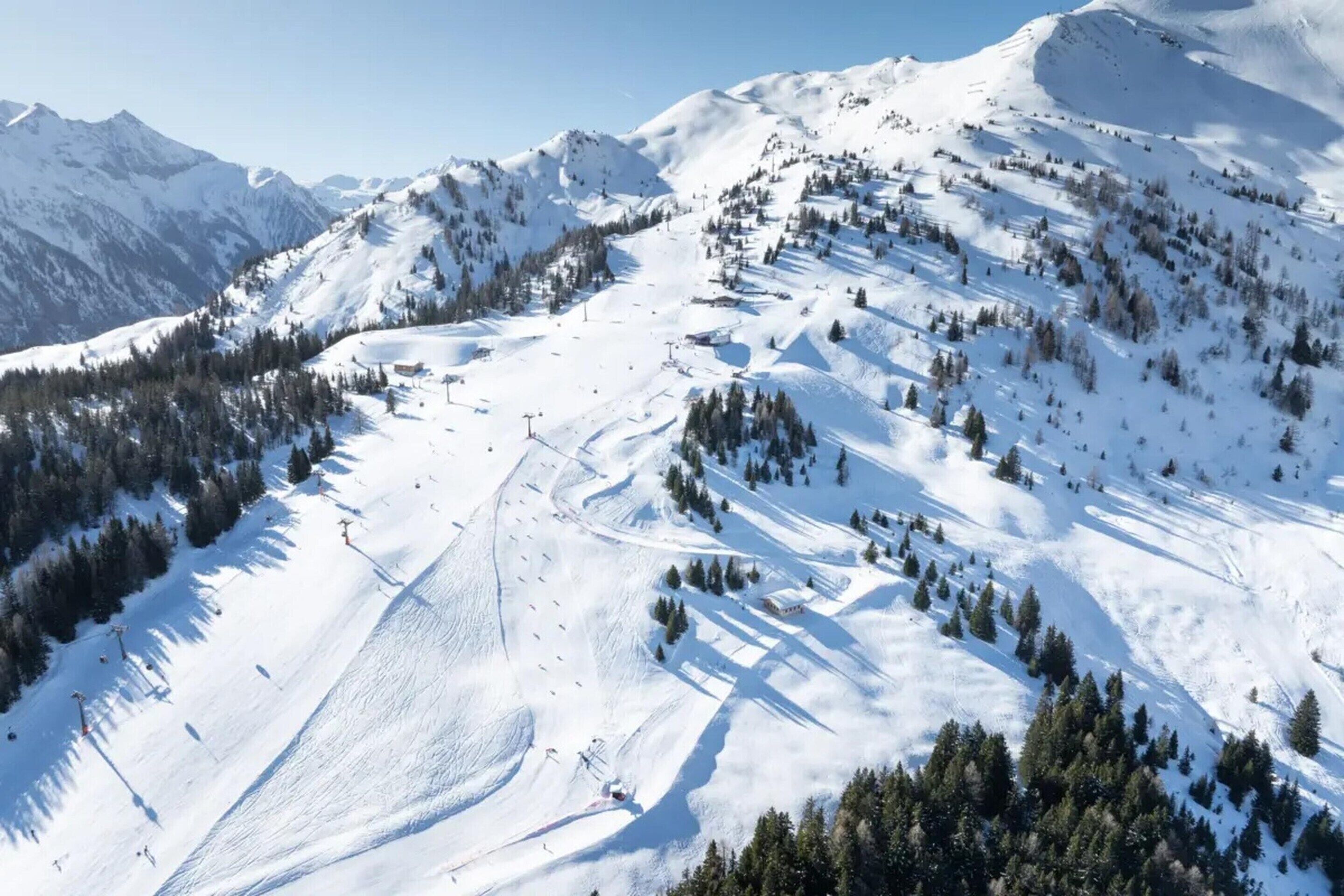 A snow-covered mountain landscape with ski slopes and trees.