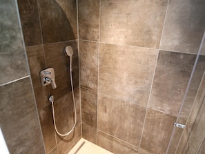 A shower area with a handheld showerhead and a wall-mounted faucet. - Comfortable Suite for 4 Guests (Rauris)