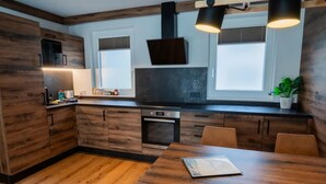 A modern kitchen with wooden cabinetry, a built-in oven, and a dining area with a table.