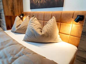 Une chambre à coucher avec une tête de lit capitonnée, un lit avec une literie beige et deux lampes de chevet.