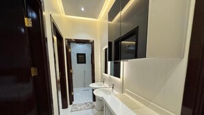 A modern bathroom with a white countertop, two sinks, and a large mirror. - الشقق الفاخره Luxury Apartments (AL Madinah AL Munawwarah)