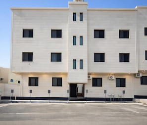 A multi-story hotel with a flat facade, evenly spaced windows, and a central entrance with steps. - الشقق الفاخره Luxury Apartments (AL Madinah AL Munawwarah)