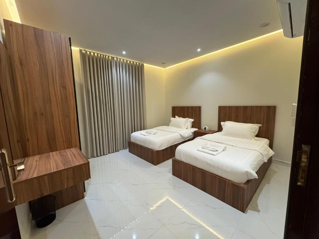 A hotel room with two beds, a wooden vanity, and a modern design.