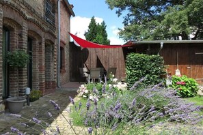 Ein Backsteinhaus mit Terrasse, Gartenmöbeln im Freien und einem Lavendelgarten.