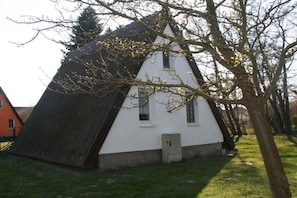 A white building with a steeply pitched roof, surrounded by trees and grass. - Finnish hut Elisabeth (Gager)
